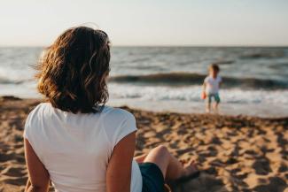 Women on beach staring at child in ocean.